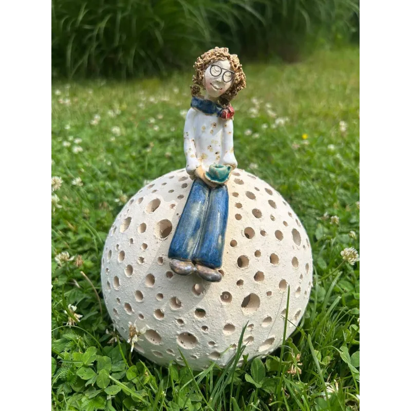 Ceramiczna figurka kobiety siedzącej na ażurowej kuli