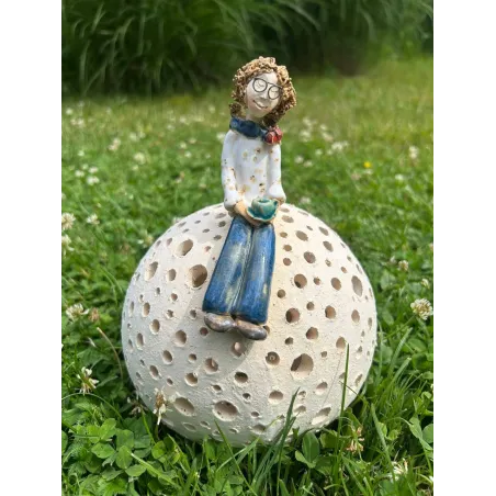 Ceramiczna figurka kobiety siedzącej na ażurowej kuli