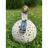 Ceramiczna figurka kobiety siedzącej na ażurowej kuli