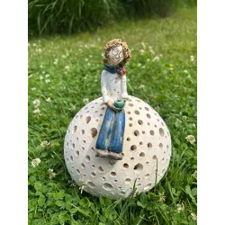 Ceramiczna figurka kobiety siedzącej na ażurowej kuli